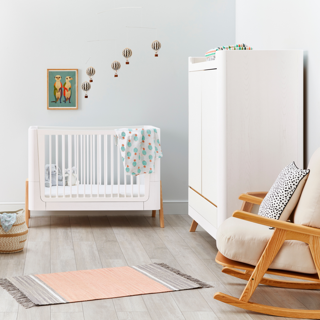 Lifestyle image of Gaia Baby Hera Wardrobe in Scandi White and Natural in a nursery. Room also has Hera Cot Bed in Scandi White and Natural and a Hera Rocking Chair