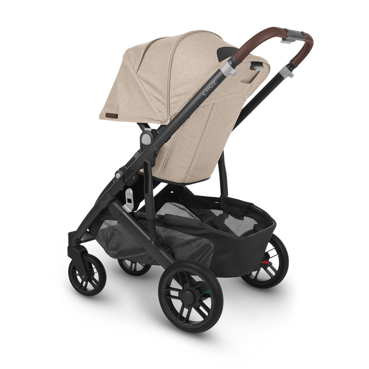 Rear angle of UPPAbaby Cruz V2 Liam stroller – beige premium pushchair with leather handlebar, extended sun canopy, and large under-seat basket for urban family travel