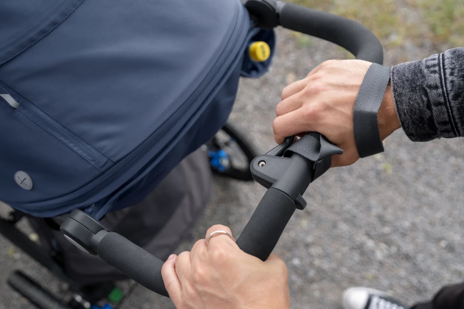 This image showcases a parent pushing the Ridge jogging stroller and using the disc handbrake system to slow the stroller down