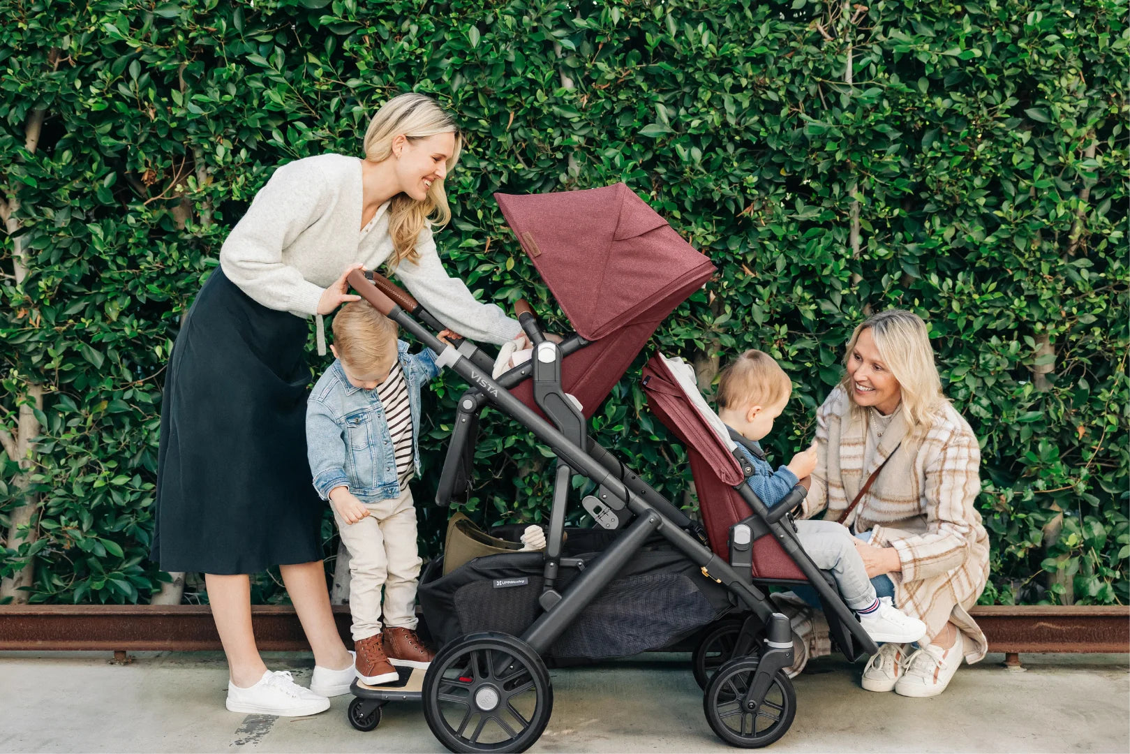 UPPAbaby Vista V2 Stroller in Lucy, used in double mode with the addition of the Piggyback Ride Along Board to hold three children.