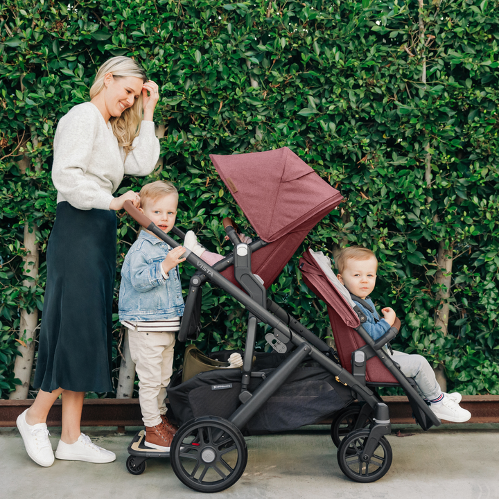 This is a lifestyle shot of a Mom out for a stroll, pushing all three of her kids in the Vista V2 with the use of the RumbleSeat and Piggyback accessories