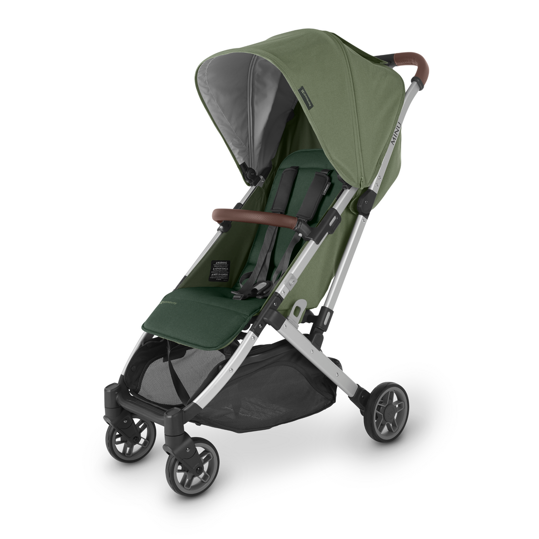 UPPAbaby Minu V2 lightweight travel stroller in Emelia which is a green fabric with chestnut REACH certified leather accents on a silver frame.  The pushchair is angled to the left