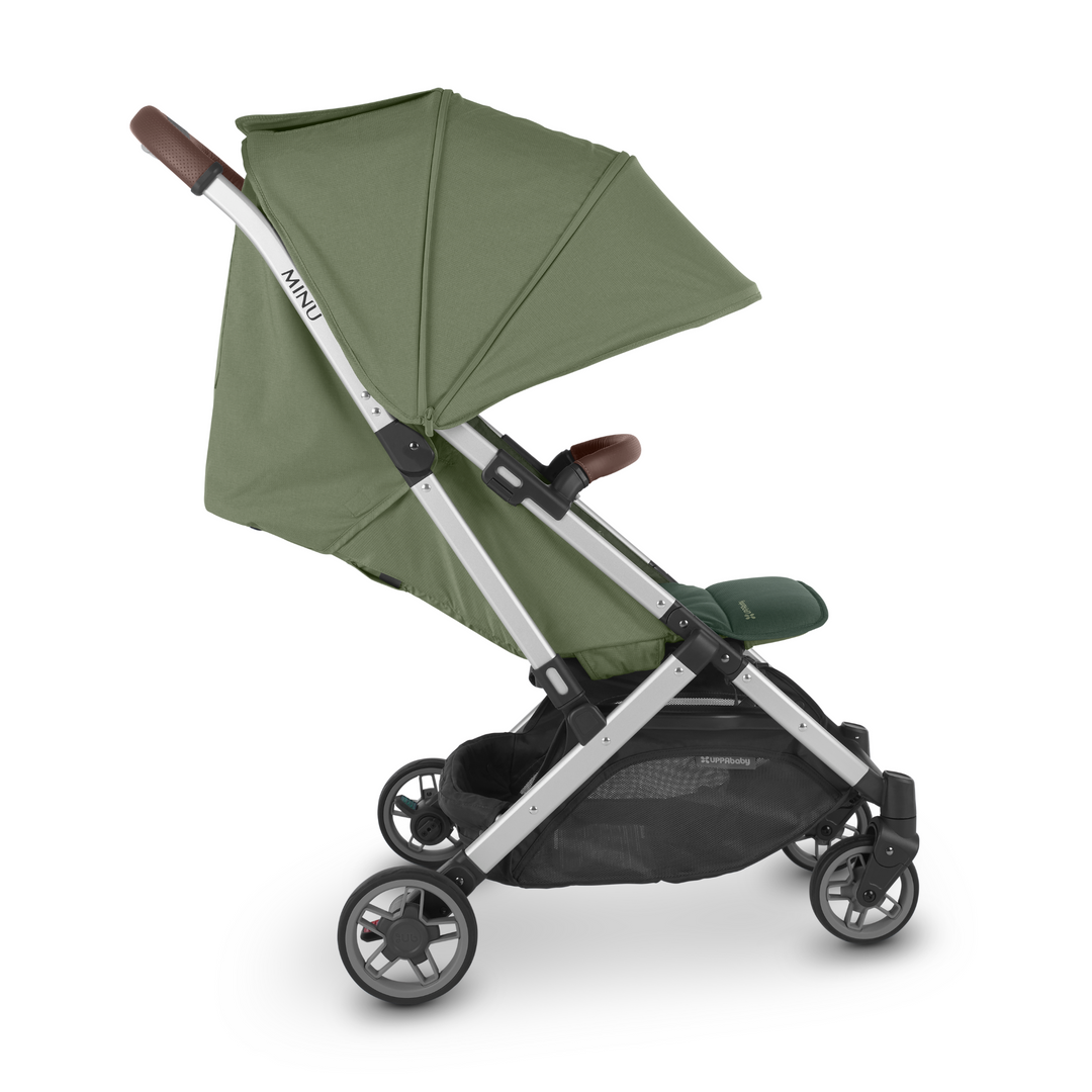 UPPAbaby Minu V2 lightweight travel stroller in Emelia which is a green fabric with chestnut REACH certified leather accents on a silver frame.  This is a side shot of the stroller, showcasing the recline, the extendable UPF 50+ sunshade and the adjustable leg rest.