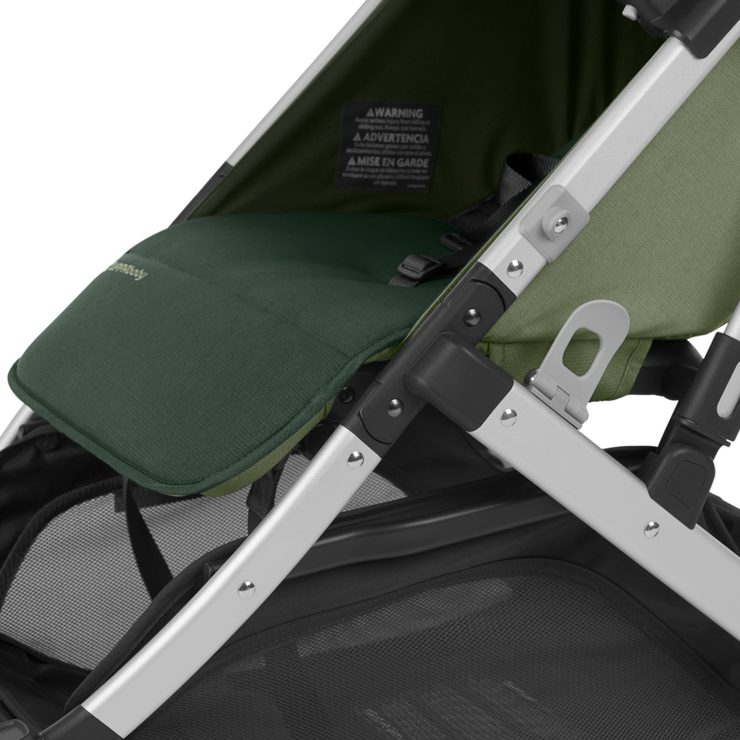 UPPAbaby Minu V2 lightweight travel stroller in Emelia which is a green fabric with chestnut REACH certified leather accents on a silver frame.  This image is a close up of the gorgeous green coloured fabric and the adjustable leg rest feature