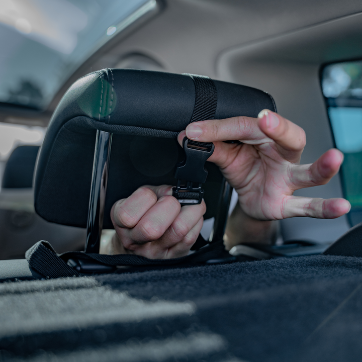 This image shows a parent attaching the mirror to the rear seat headrest.