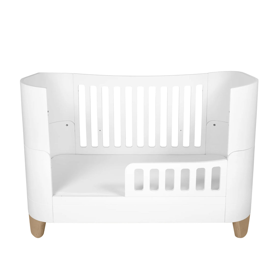 Gaia Baby Serena toddler bed with low toddler rail and natural wooden legs, shown in protective high-back configuration, featuring the brand’s signature curved panels and safe slatted design for transitioning toddlers.