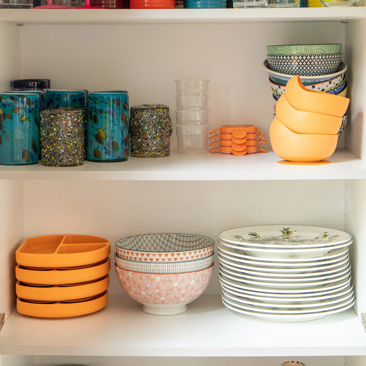 Feedi silicone suction plates and bowls neatly stacked in a kitchen cupboard — BPA-free, dishwasher-safe baby feeding essentials for modern families.