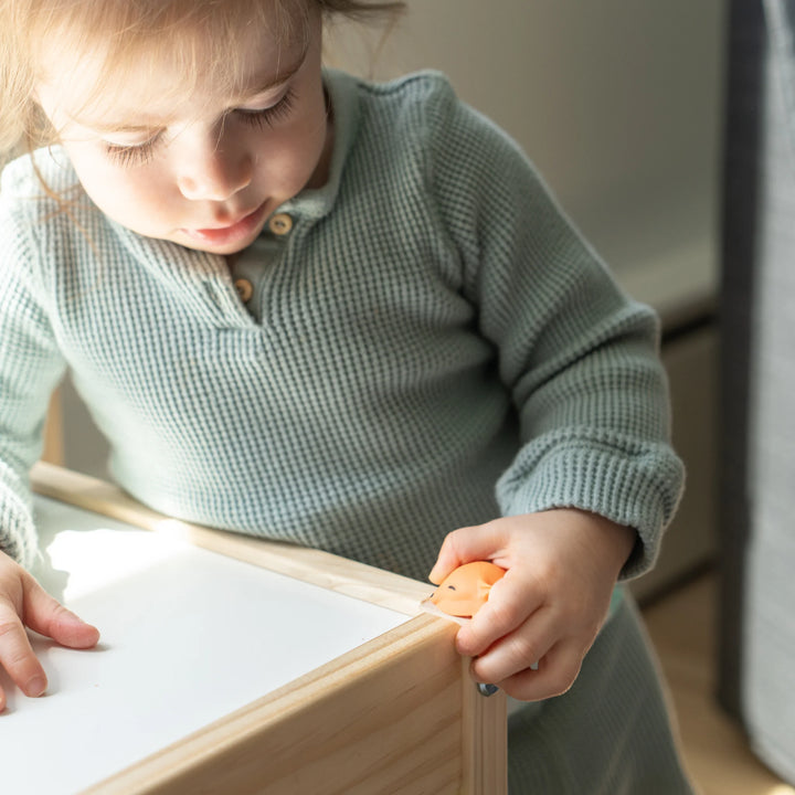 Toddler using Foxii by Quark silicone corner protector in fox design on wooden furniture, baby-proofing safety accessory to prevent bumps and protect little explorers at home