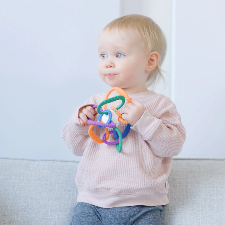 Toddler holding Thiingy by Quark – colorful silicone baby teething toy with interlocking textured rings for sensory play, teething relief, and fine motor skill development – BPA-free and baby-safe
