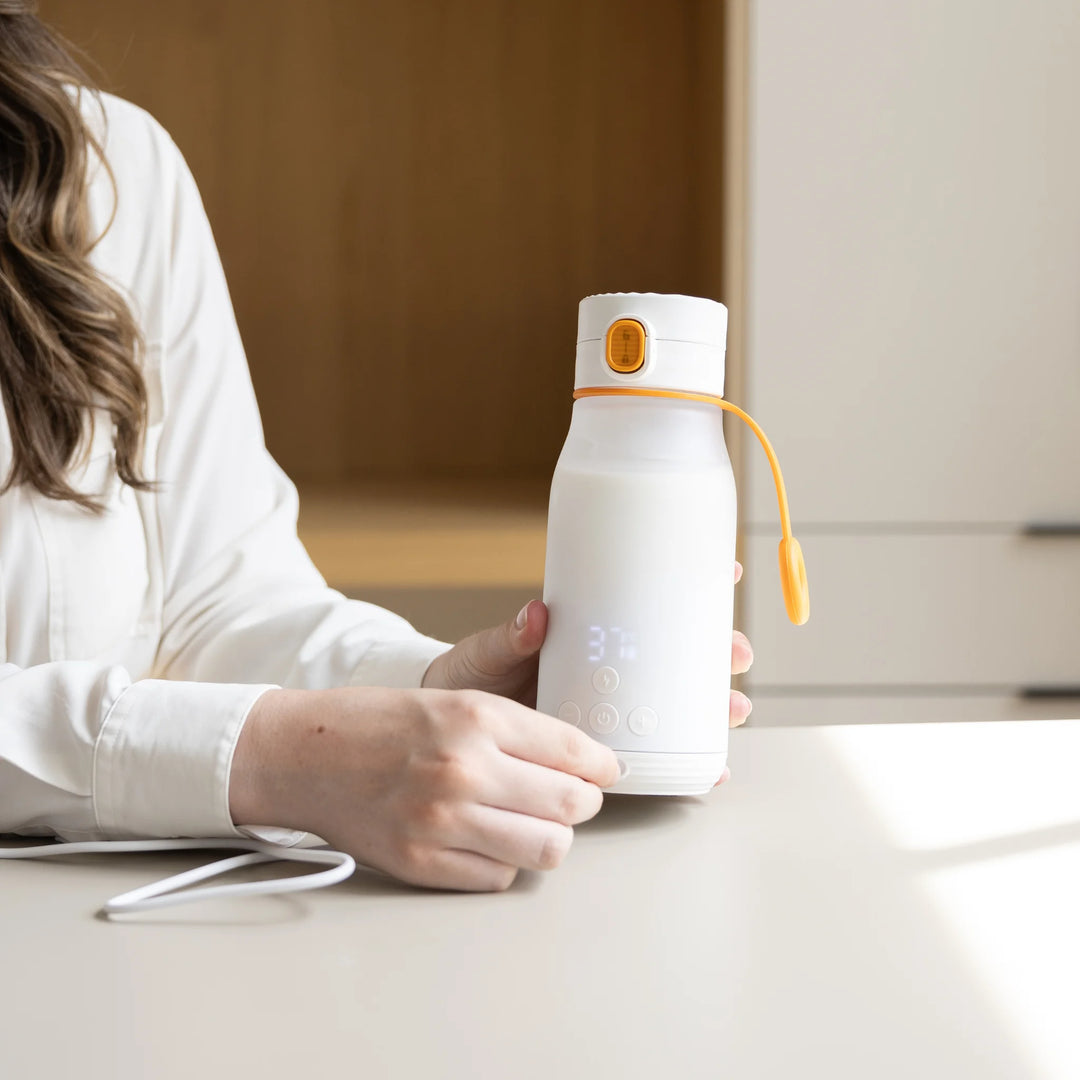 Parent using Buubi by Quark smart portable baby bottle warmer with digital temperature display, rechargeable milk heating device designed for quick and safe baby feeding at home or on the go.