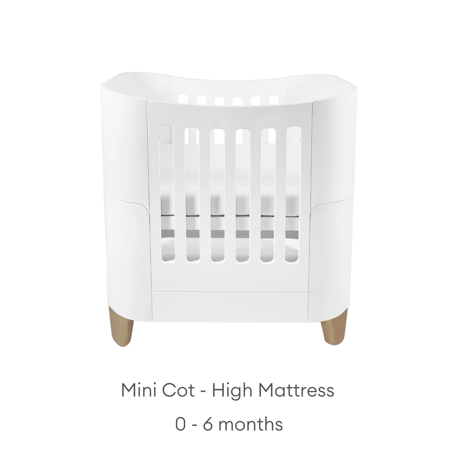 “Serena Mini Cot with natural wooden legs shown in the high-mattress position for newborns aged 0–6 months, featuring a modern white curved design and breathable slatted sides.