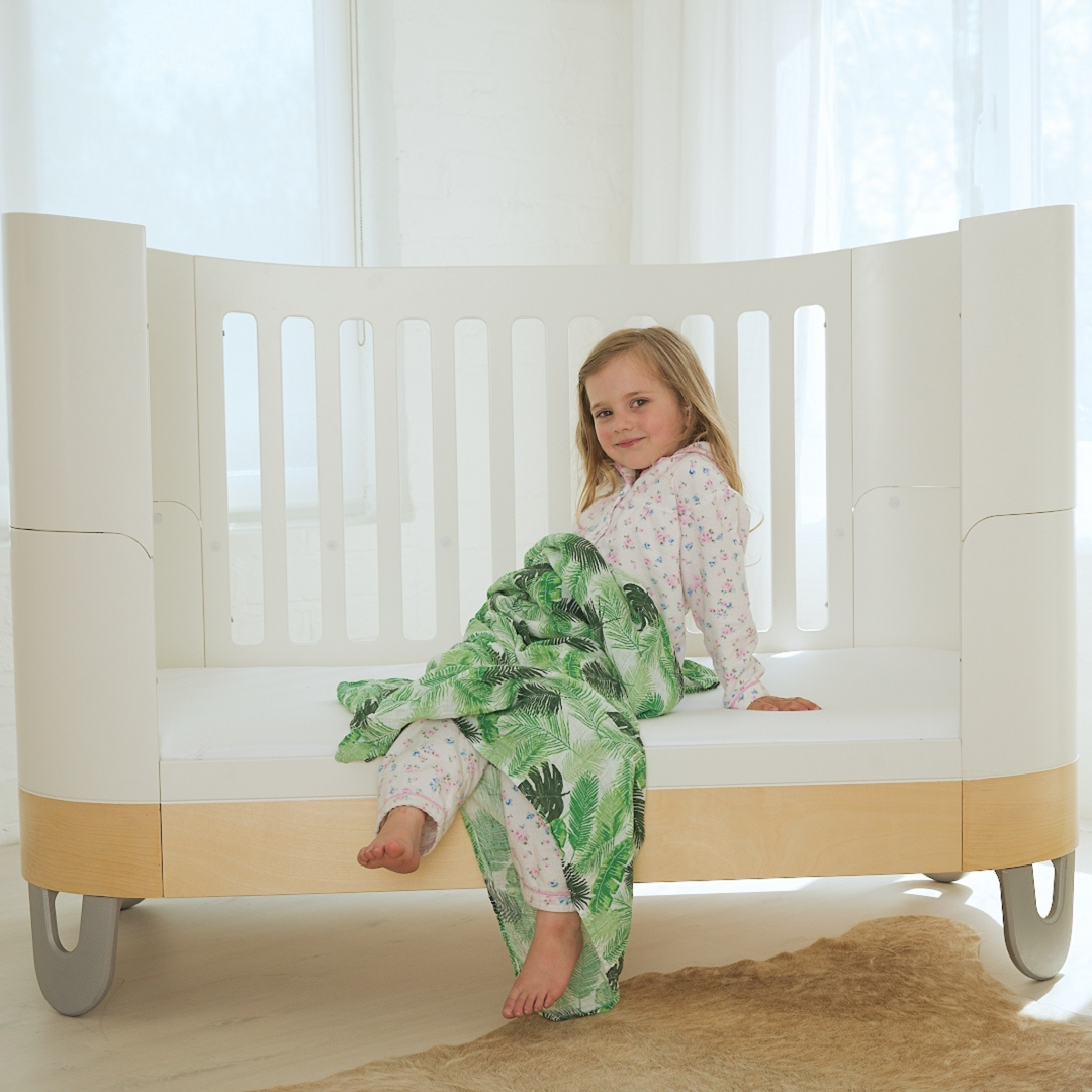Serena Cot Bed White and Natural as Toddler Bed lifestyle image of little girl sitting on the bed