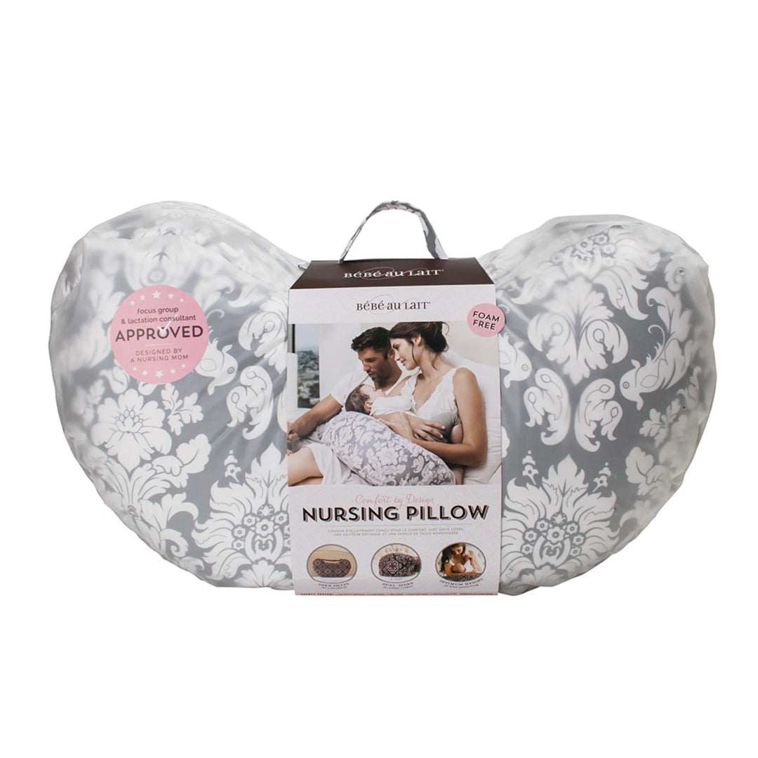 Bebe au Lait Complete Nursing Pillow in Chateau Silver design, shown in packaging with grey and white damask print, foam-free fill, lactation consultant approved badge, and imagery of parents using the ergonomic breastfeeding support pillow.
