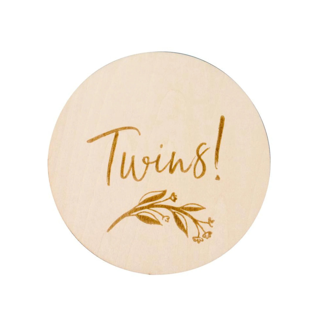 Wooden ‘Twins!’ milestone announcement disc with engraved botanical design on a white background, newborn twins gender reveal and birth announcement photography prop.
