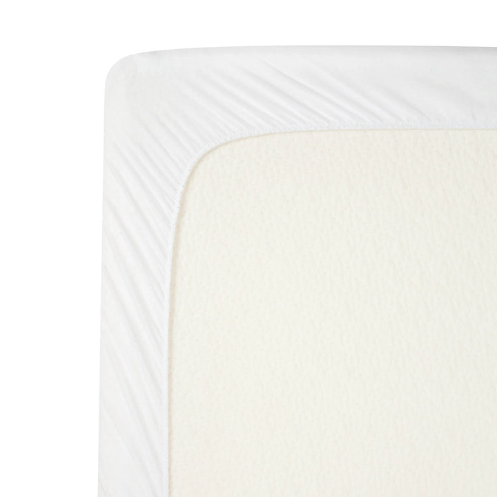 Close-up of the ClevaMama brushed cotton waterproof mattress protector fitted securely over a baby mattress, showing soft breathable fabric and elasticated corner for a snug fit.