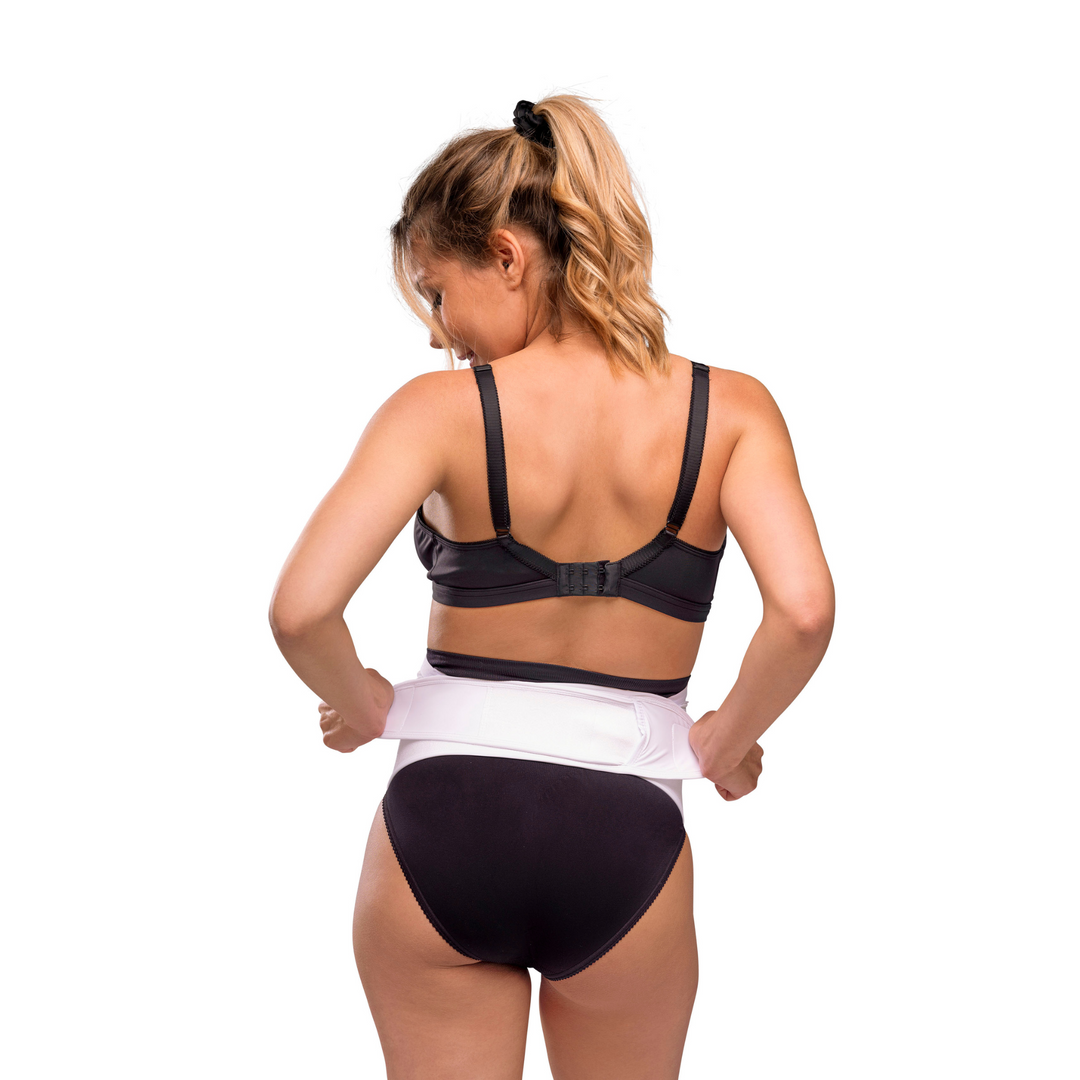 This is an image showing the model tightening the velcro straps of the maternity support belt to fit.