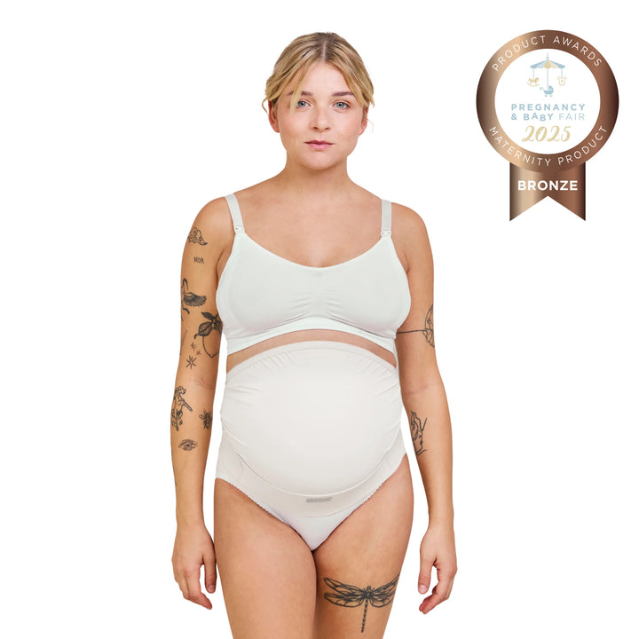 Carriwell adjustable maternity support belt in white worn by pregnant model, providing comfortable bump and back support during pregnancy, award-winning maternity belly support belt for everyday wear.