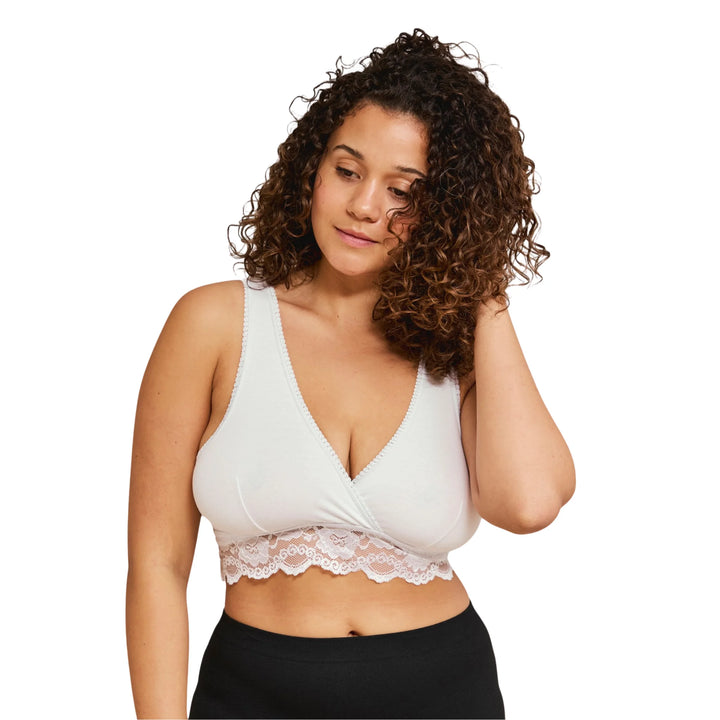 Woman wearing a white Carriwell crossover sleeping and nursing bra with lace trim, offering soft support and easy breastfeeding access for pregnancy and postpartum.