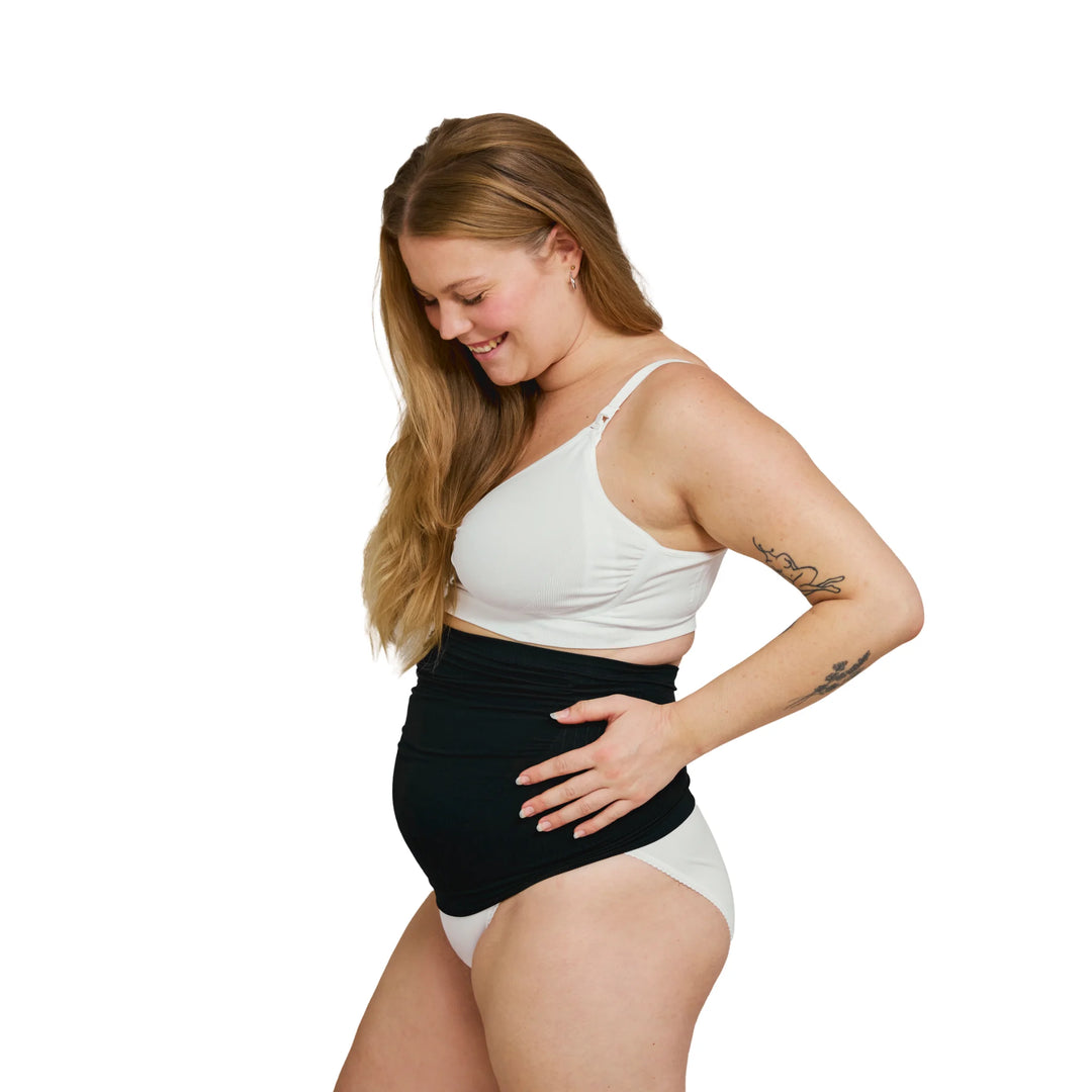 Side view of pregnant woman wearing a black Carriwell maternity support band, providing adjustable over-bump and lower back support for comfort during pregnancy.