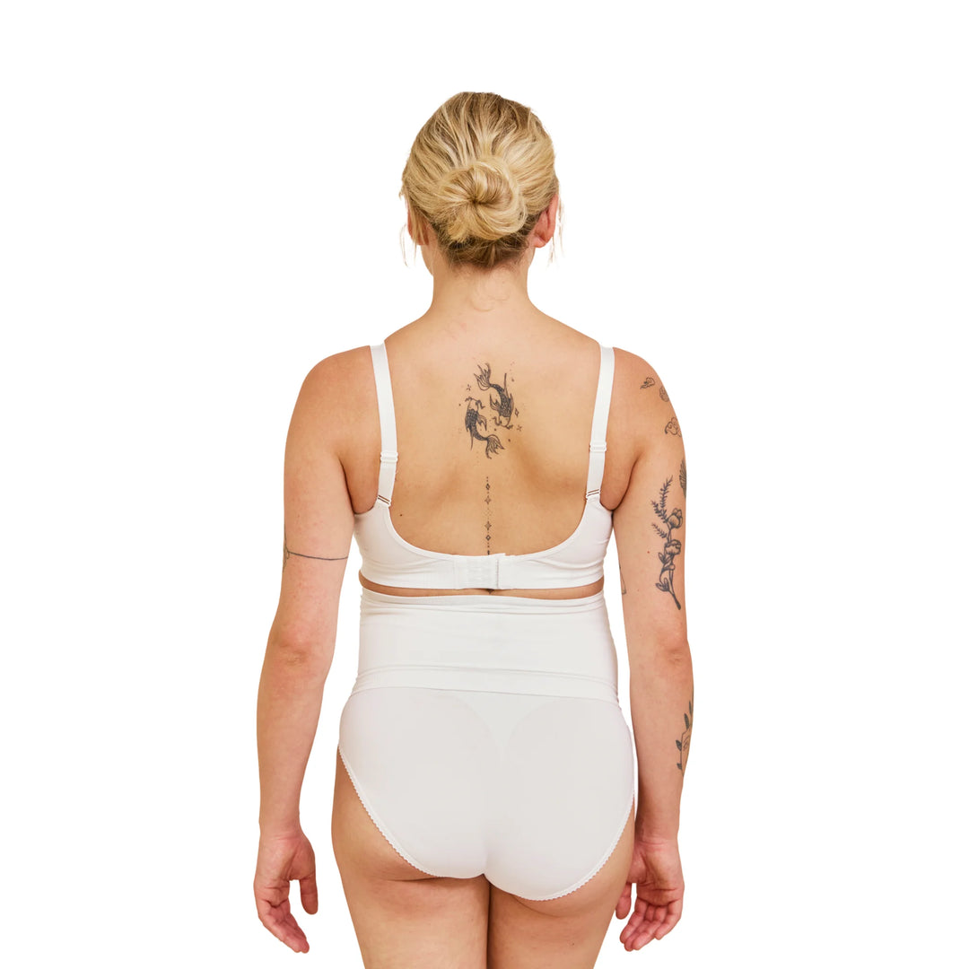 Back view of pregnant woman wearing white Carriwell maternity support band, showing smooth seamless fit and adjustable design for gentle lower back and abdominal support during pregnancy.