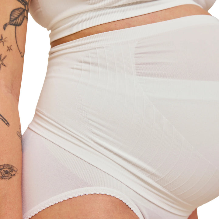 Close-up of white Carriwell maternity support band worn over pregnancy bump, showing seamless breathable fabric and gentle compression for comfortable belly and lower back support during pregnancy.