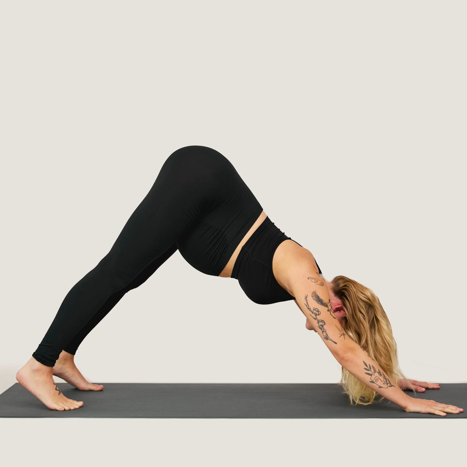 Person wearing maternity leggings in a yoga pose on a gray mat with a plain background
