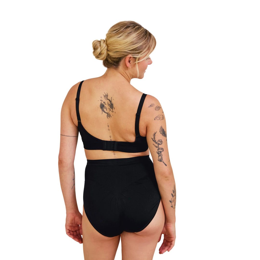 Back view of pregnant woman wearing black Carriwell maternity support panty, providing gentle lower back and belly support for comfortable wear during pregnancy.