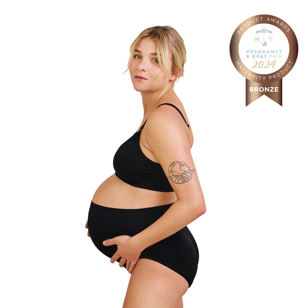 Side view of pregnant woman wearing black Carriwell maternity support panty, providing gentle belly and lower back support during pregnancy, with Pregnancy & Baby Fair award badge.