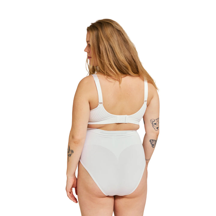 Back view of pregnant woman wearing white Carriwell maternity support panty, designed to provide gentle belly and lower back support for comfortable wear during pregnancy.