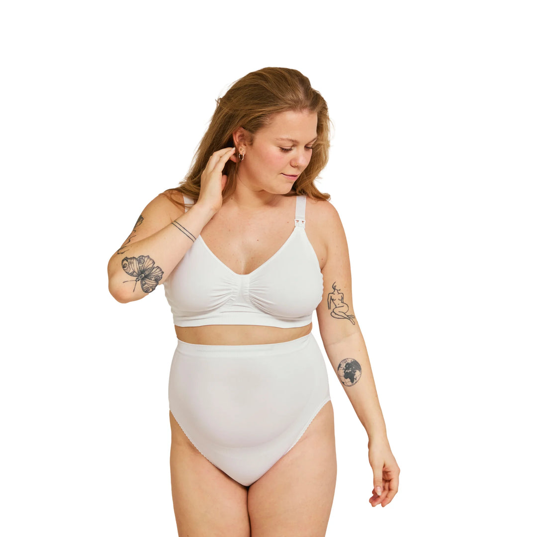 Front view of pregnant woman wearing white Carriwell maternity support panty, designed to support the growing belly and provide comfortable everyday wear during pregnancy.
