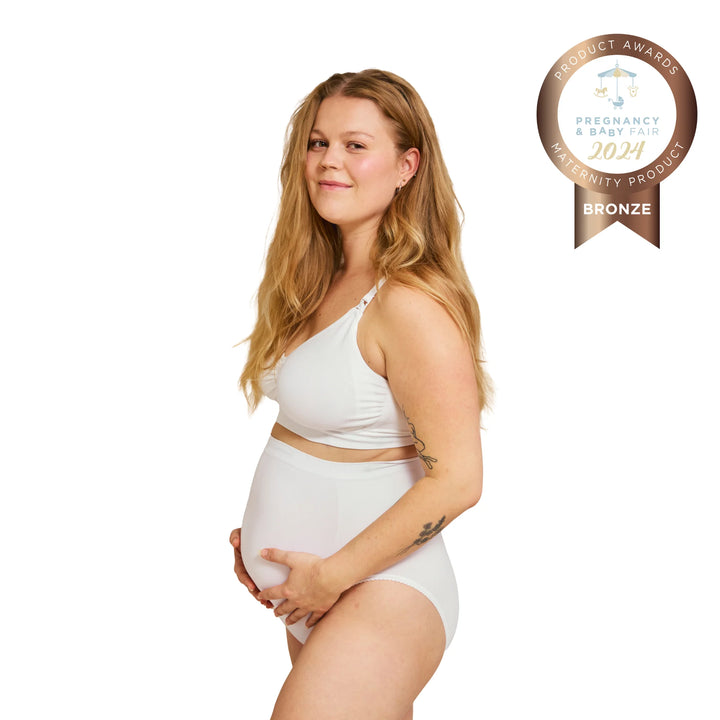 Side view of pregnant woman wearing white Carriwell maternity support panty, providing gentle belly and lower back support during pregnancy, with Pregnancy & Baby Fair award badge.