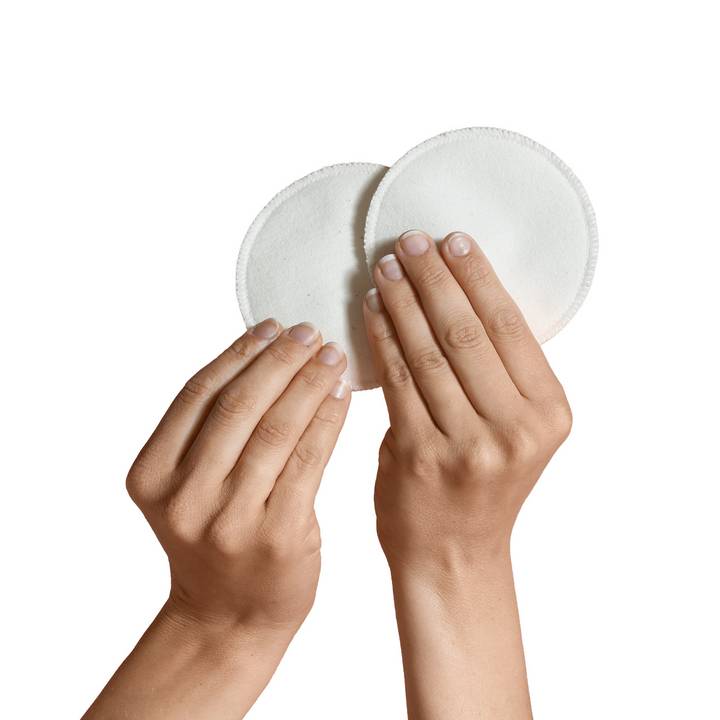 This image shows two hands holding up the Carriwell organic cotton breast pads.