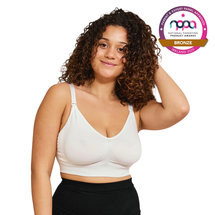 Woman wearing a white breastfeeding bra with a bronze NPPA badge on a white background