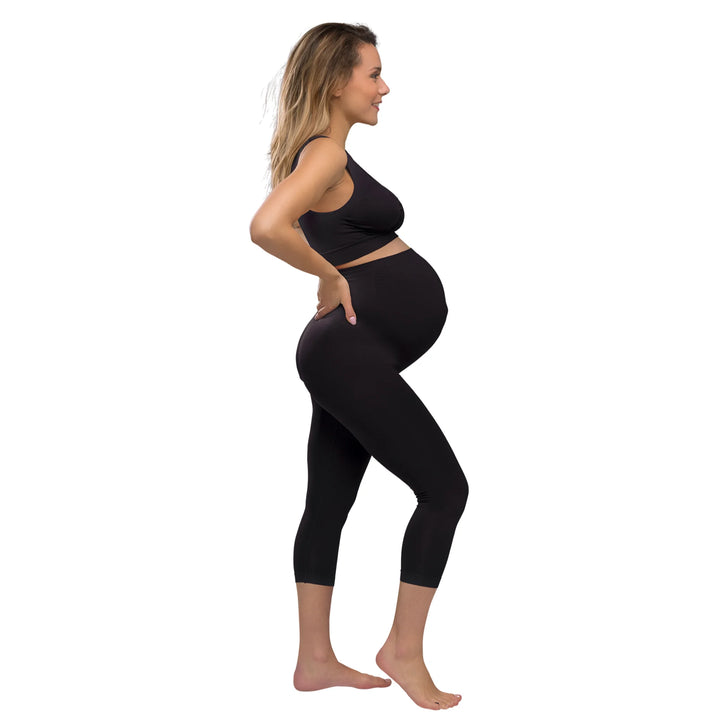 Side view of model wearing Carriwell three-quarter length maternity support leggings in black, showing the high-waisted over-bump fit designed to support the growing belly during pregnancy.