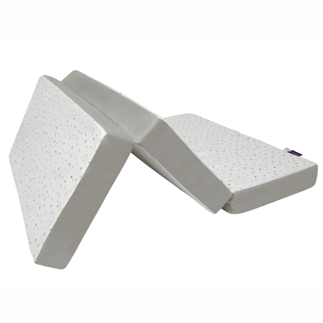 A foldable 3-in-1 travel cot mattress in white and grey displayed in a partially folded position on a white background, designed for portable baby sleep comfort with supportive foam sections and compact travel-friendly functionality.
