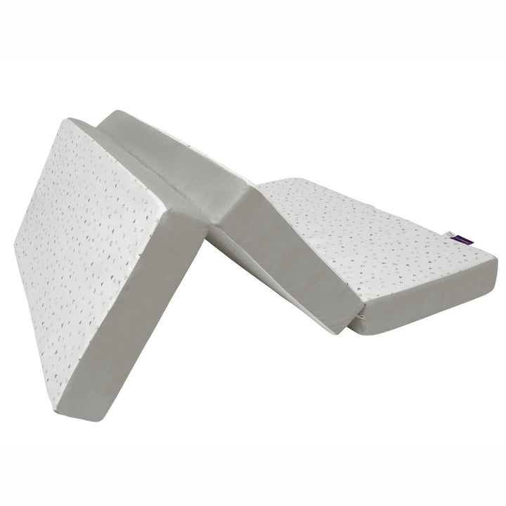 A foldable 3-in-1 travel cot mattress in white and grey displayed in a partially folded position on a white background, designed for portable baby sleep comfort with supportive foam sections and compact travel-friendly functionality.