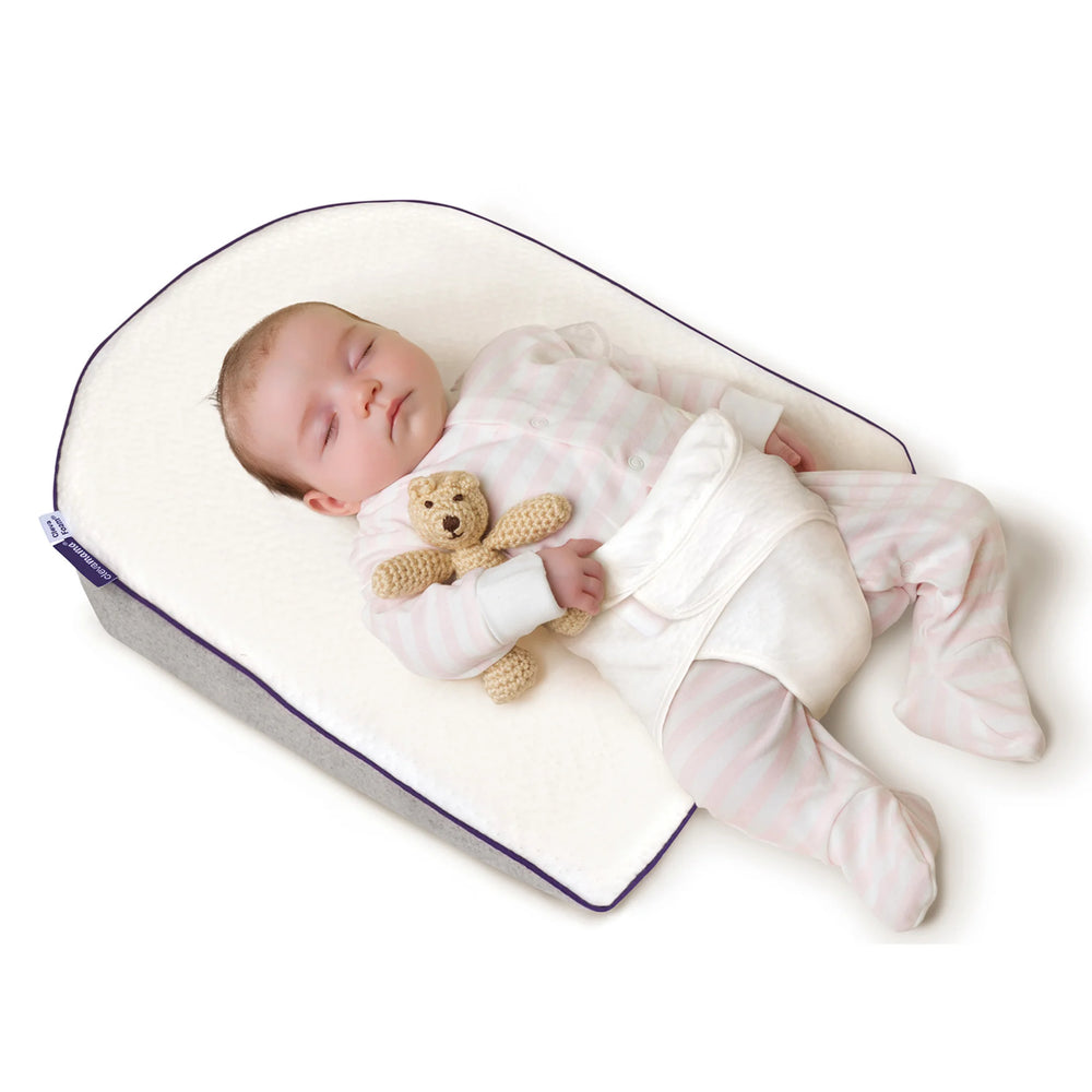 Baby sleeping peacefully on ClevaMama ClevaFoam Elevated Support — breathable and supportive baby sleep positioner designed to reduce reflux, congestion, and colic, providing gentle elevation and safe, comfortable rest.