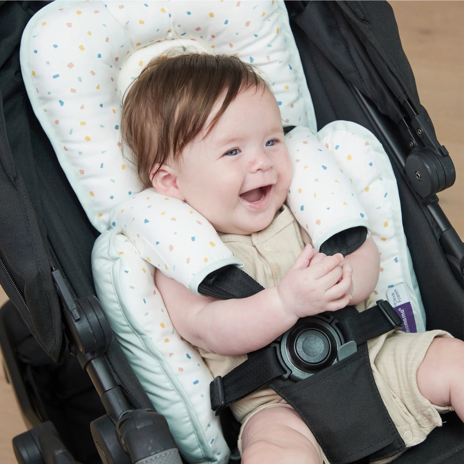 ClevaMama ClevaFoam Head and Neck Support Terrazzo design — smiling baby sitting in stroller using ergonomic ClevaFoam head and body cushion. Soft, breathable, and hypoallergenic newborn insert providing head and neck stability to prevent flat head syndrome. Ideal baby support pillow for car seats, strollers, and bouncers.