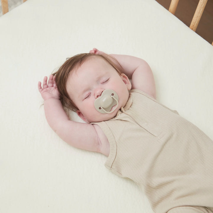 Baby sleeping peacefully on Clevamama Waterproof Support Mattress – breathable, hypoallergenic baby mattress with waterproof protection, reflex support foam, and washable removable cover for safe and comfortable sleep.