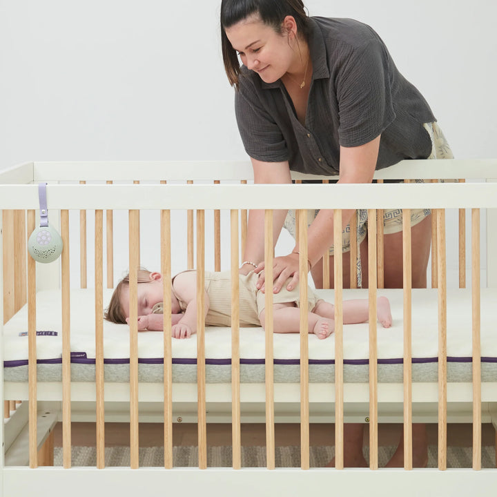 Mother soothing baby sleeping on Clevamama Waterproof Support Mattress in cot – hypoallergenic, breathable, and durable baby mattress with waterproof protection and removable washable cover, providing safe and comfortable sleep support.