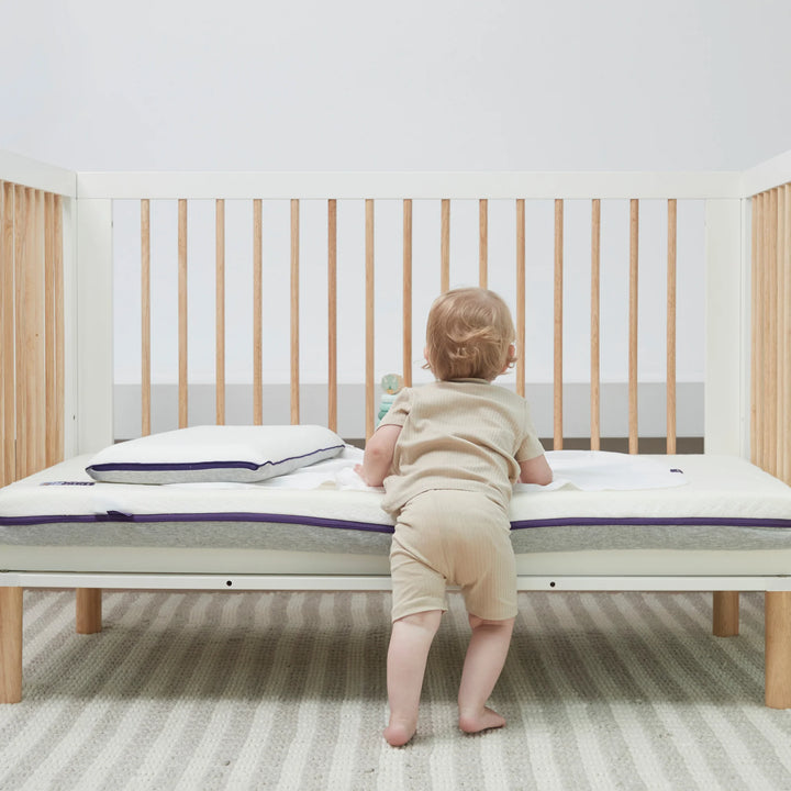 Toddler standing in cot with Clevamama ClevaFoam Waterproof Support Mattress – premium breathable baby mattress with waterproof protection, hypoallergenic reflex support foam, and removable washable cover for safe, hygienic, and comfortable sleep support.