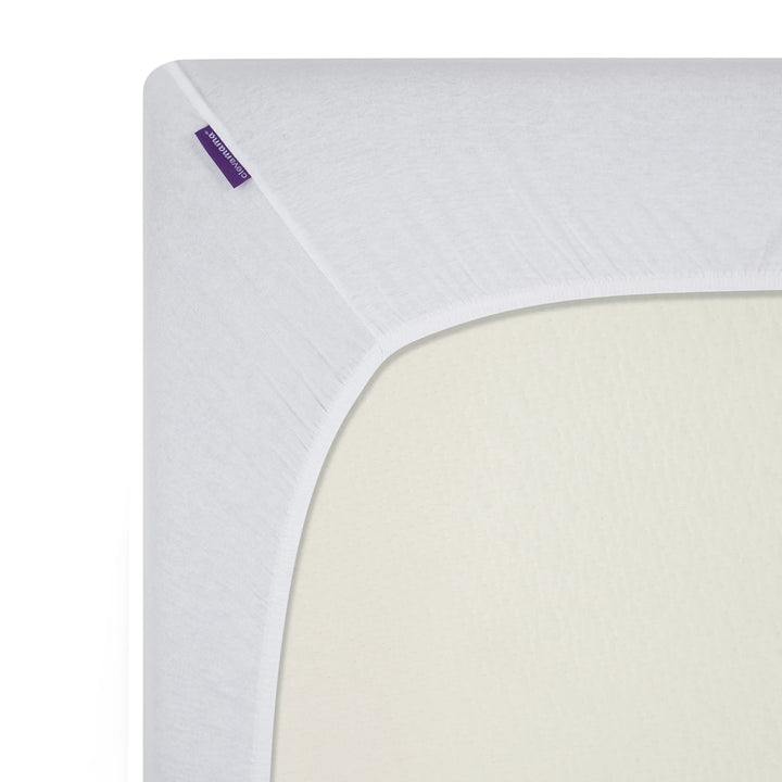 Close-up of ClevaMama white jersey cotton fitted cot bed sheet showing snug corner fit and soft, breathable stretch fabric.