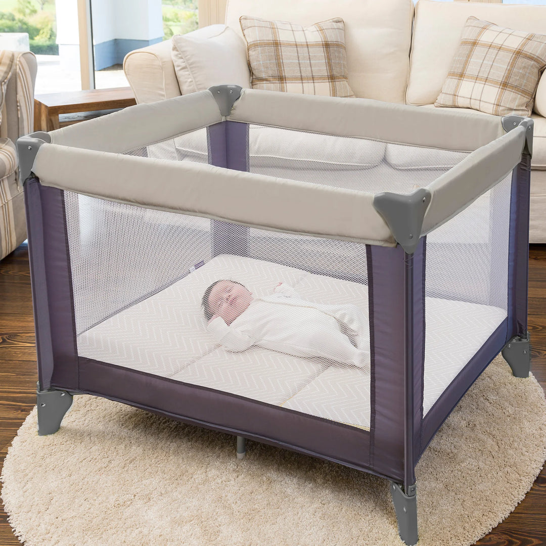 Baby in a purple and gray playpen with ClevaMama mattress in a living room setting.