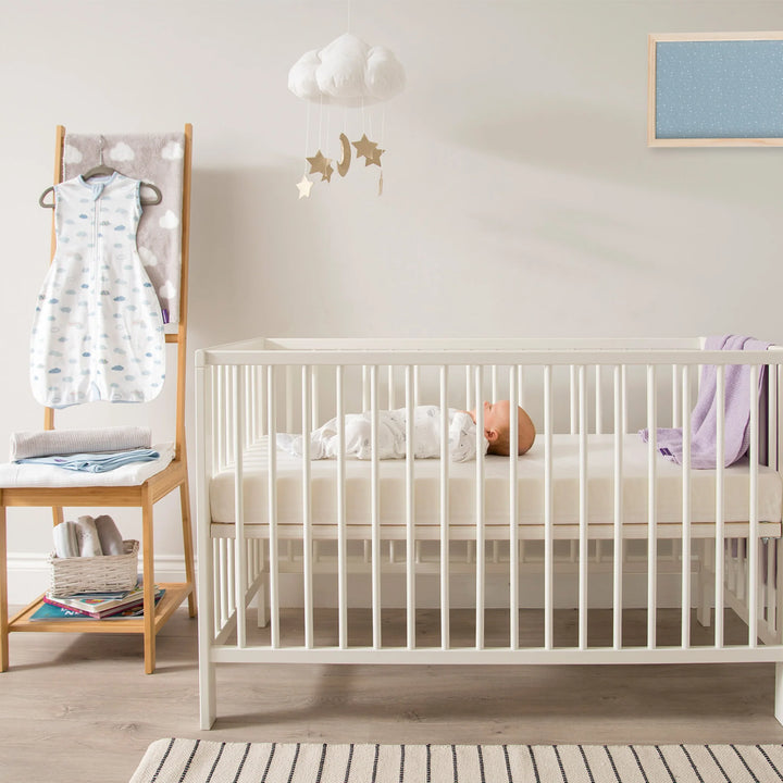 Baby sleeping peacefully on Clevamama Waterproof Support Mattress in white cot, designed for newborn safety and comfort. Hypoallergenic, breathable, and durable baby mattress with 100% waterproof protection, providing hygienic support for infants and toddlers. Premium asthma and allergy-friendly cot mattress ideal for safe baby sleep.