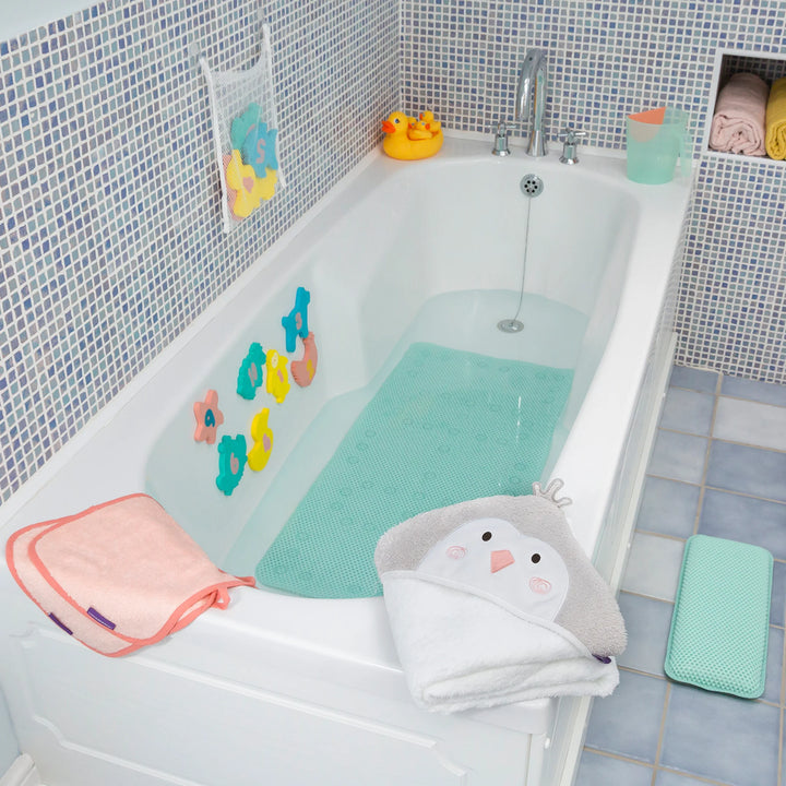 Bathroom scene with a teal bath mat in the tub, matching kneeling cushion on the floor, and baby bath toys