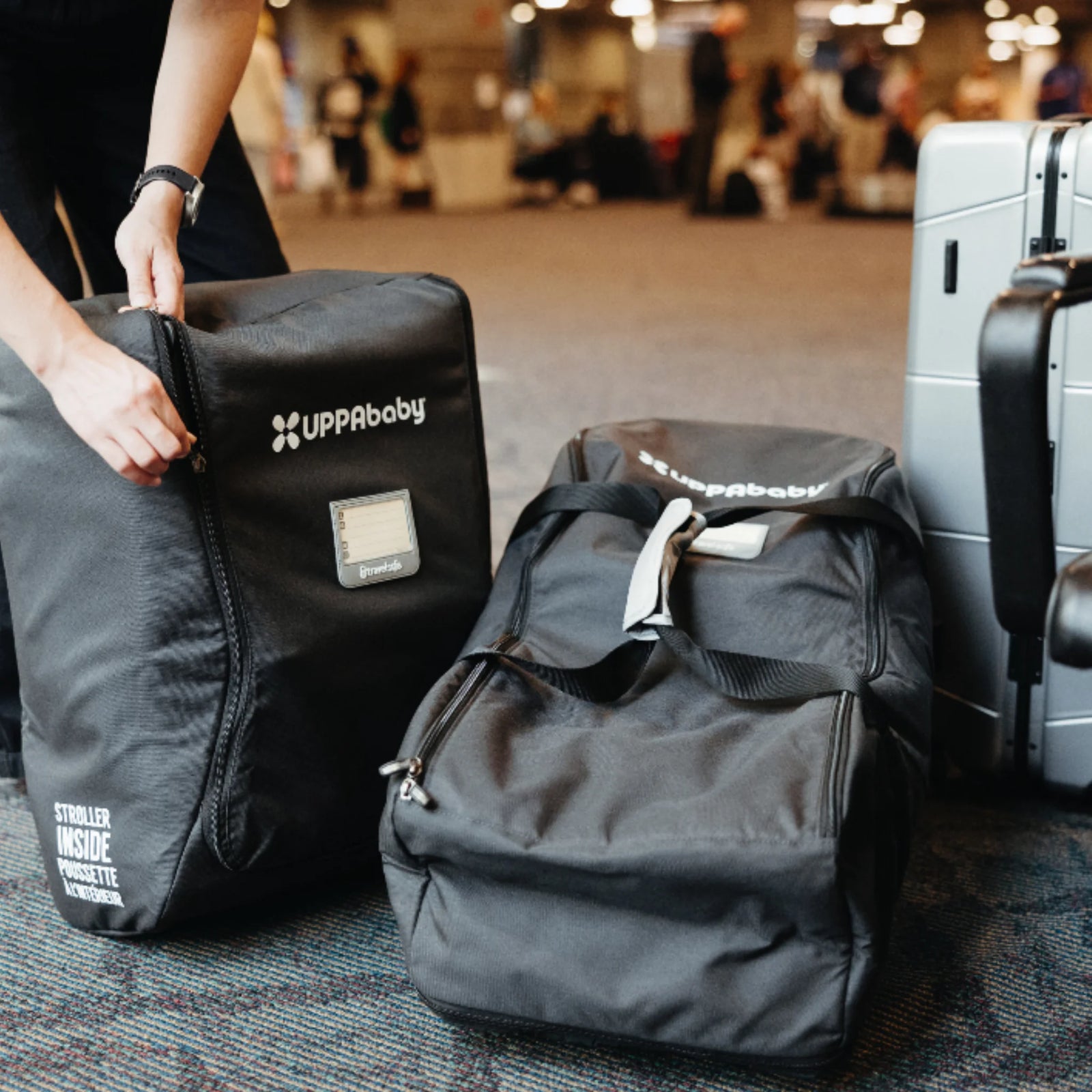 UPPAbaby MESA i-Size car seat travel bag at the airport beside luggage, ready for travel.