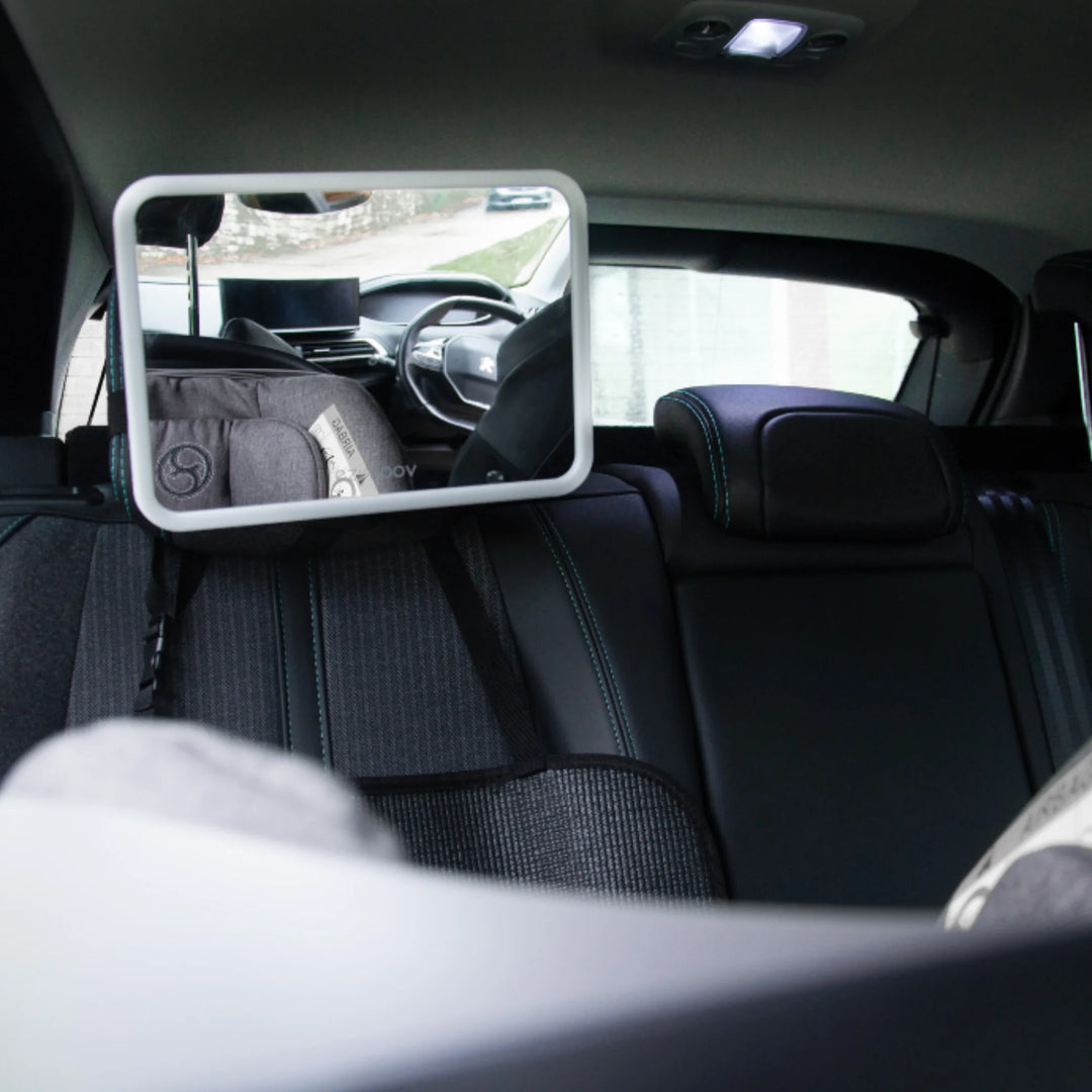 EziMoov LED Pro baby car seat mirror securely installed on rear headrest, providing a clear view of a rear-facing car seat for safer baby monitoring while driving.