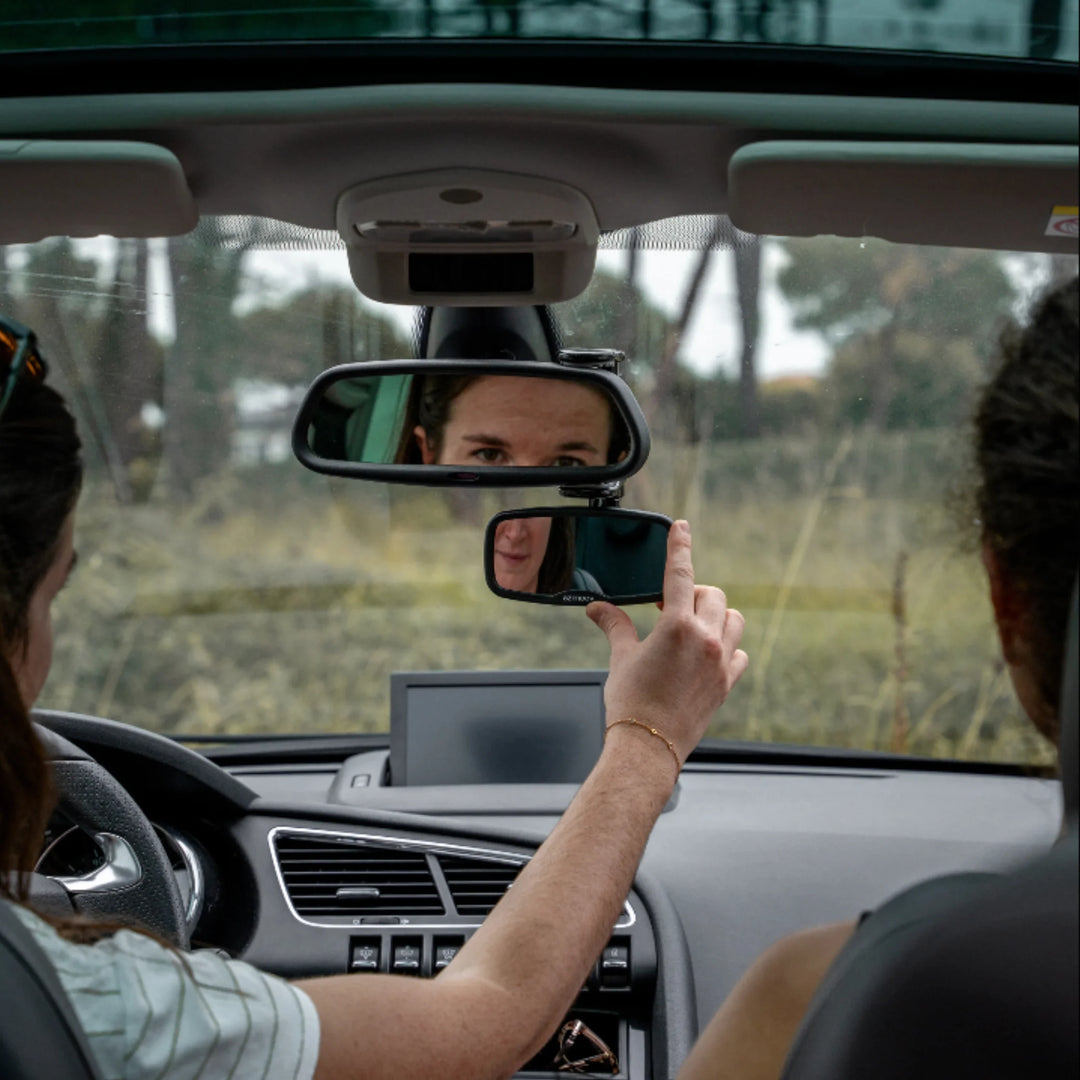 Parent adjusting Ezimoov clip-on rear-view baby mirror inside car to monitor child in back seat, showing adjustable safety mirror installation for improved visibility and safer driving.
