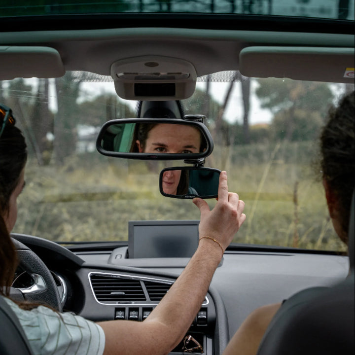 Parent adjusting Ezimoov clip-on rear-view baby mirror inside car to monitor child in back seat, showing adjustable safety mirror installation for improved visibility and safer driving.