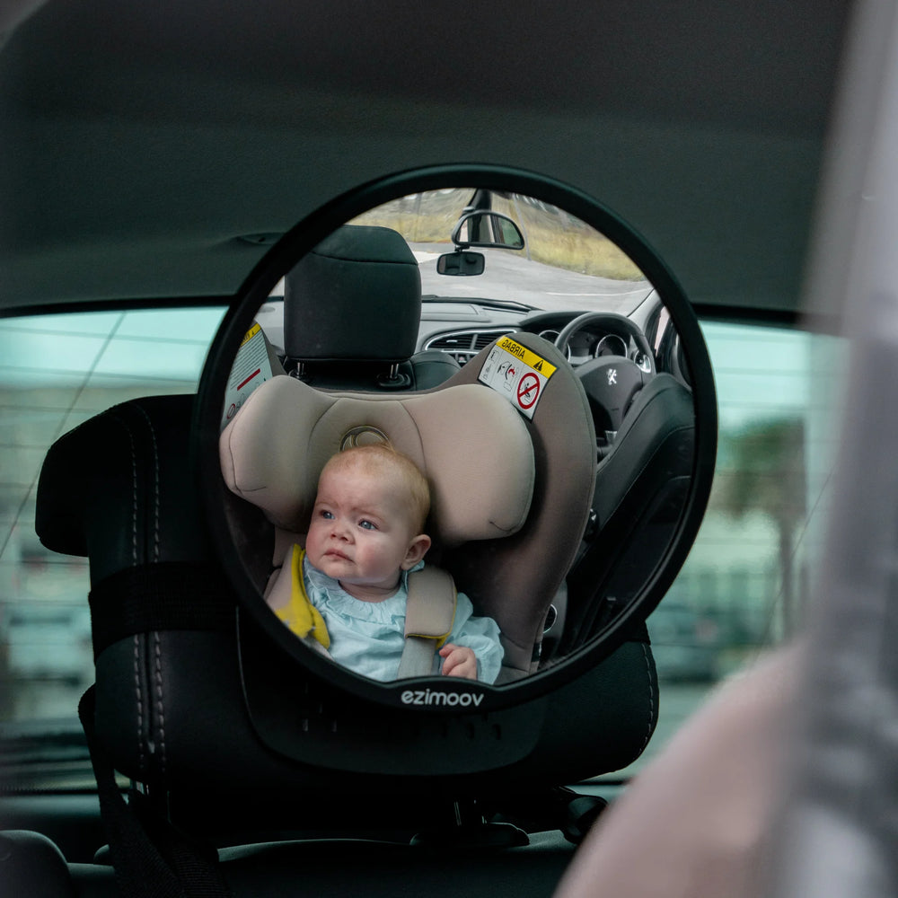 This image shows the Ezimoov Round Mirror fitted in a car, showing a baby in their car seat in the reflection.